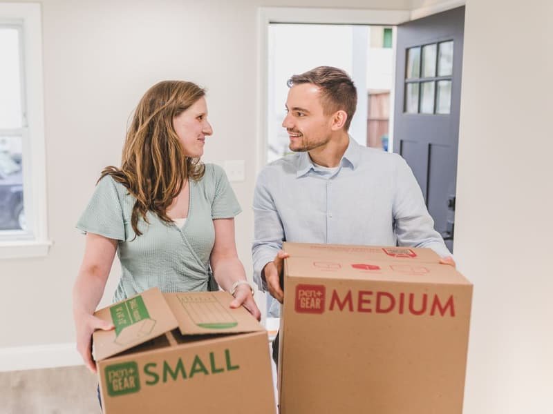 Happy couple carrying boxes into their new home