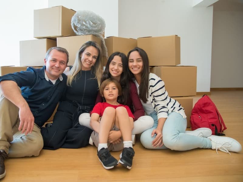 Happy family relaxing among boxes in their new home