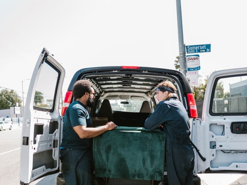 Movers loading furniture into a closed van